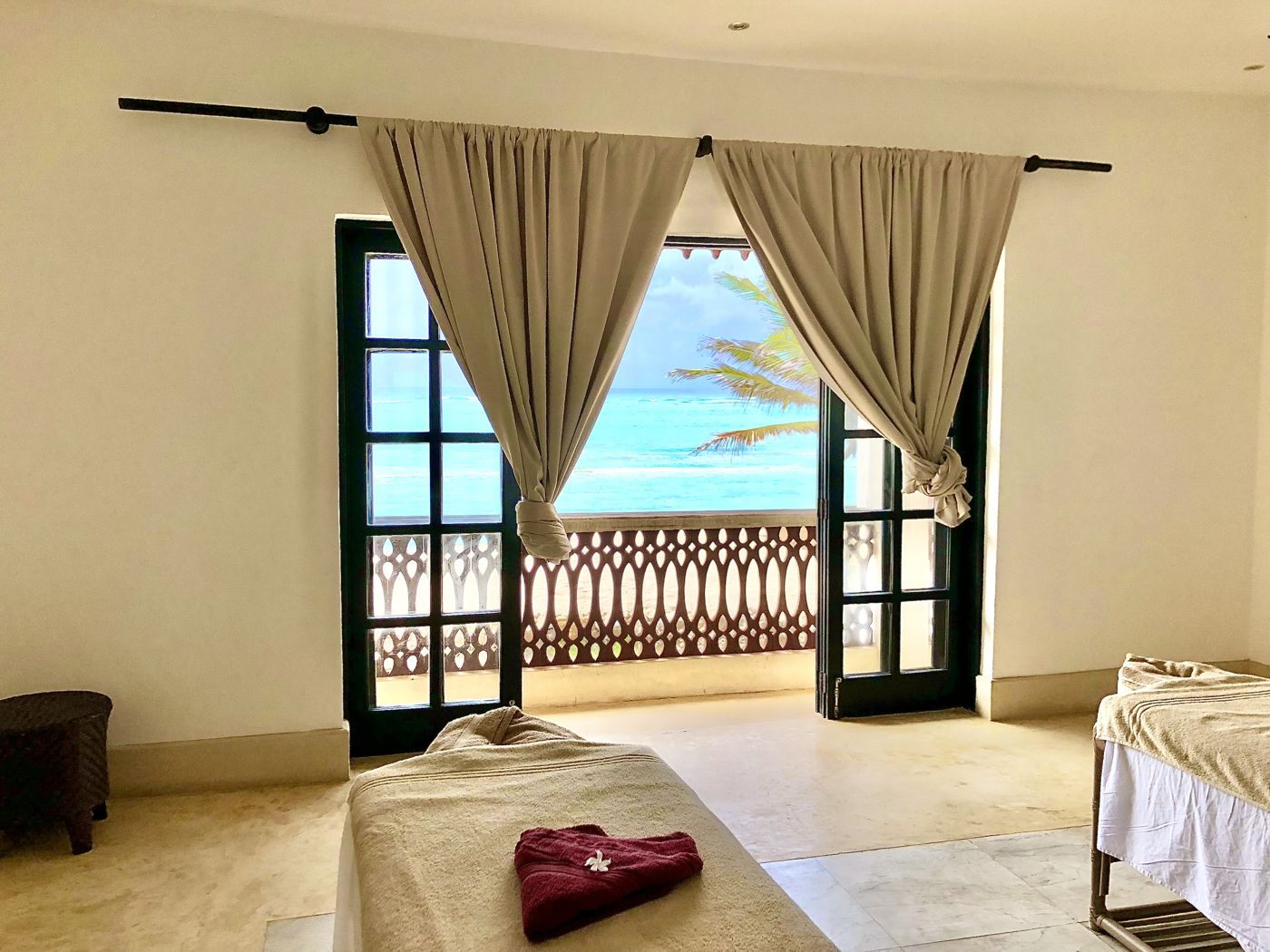 Open balcony doors onto a turquoise Indian Ocean beach from a coastal spa room